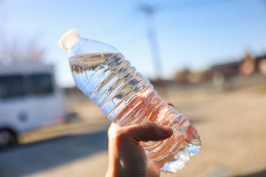 Arka planda eli olan plastik bir şişe.
