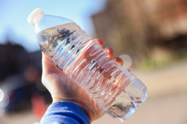 Şehirde plastik su şişesi olan bir kadın, yakın plan.