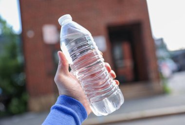 Arka planda plastik su şişesi olan kadın eli. temiz ortam