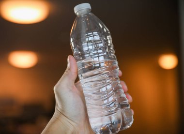 Bir kadın elinde bir şişe su tutuyor, yakın plan.