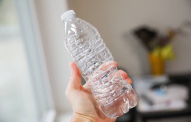 Plastik şişeyle şişeyi tutan kadın.