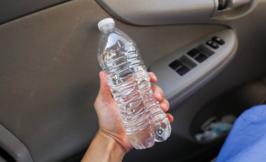 Elinde şeffaf bir şişe tutan bir kadın.