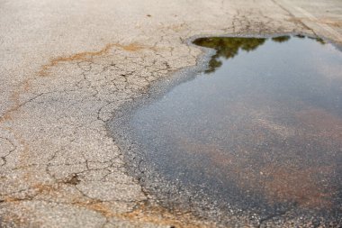 Bozuk su birikintisi olan asfalt yol