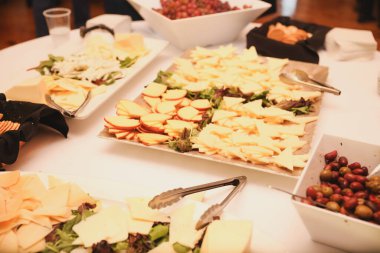 Yemek, atıştırmalık, atıştırmalık, peynir, üzüm, peynir ve şarap dolu bir masa.