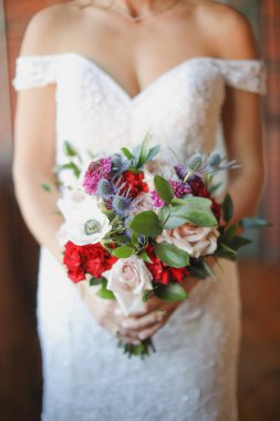 Gelin elinde kırmızı güllerle buket tutuyor, düğün günü.