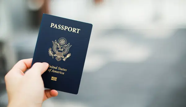 Elinde Amerikan bayrağı olan bir pasaport tutuyor.
