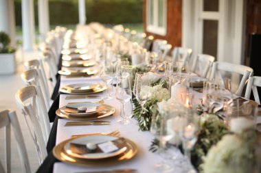 Masa seti beyaz tabaklar, çatal bıçak takımı ve gözlüklerle.