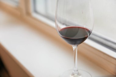 Pencerenin kenarında bir kadeh kırmızı şarap.