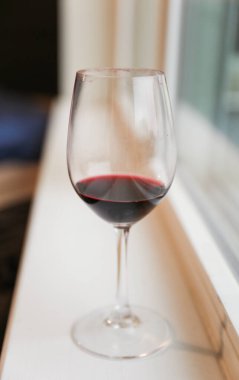 Pencerenin kenarında bir kadeh kırmızı şarap.