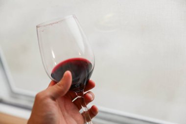 kırmızı şarap bir camın içinde, bir elin içinde.