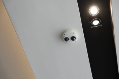 Siyah bir duvardaki beyaz güvenlik kamerası..