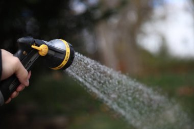 Adam hortumu su spreyiyle yıkıyor..