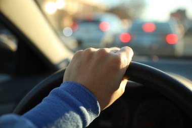 Kadın eli ve araba direksiyonu yolda.