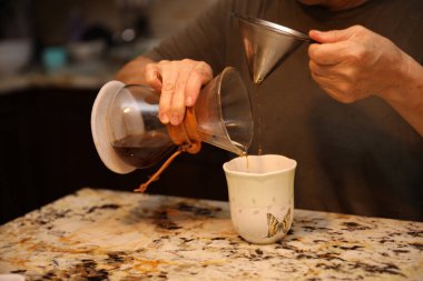 Kahve bardağına kahve dolduran barmen.