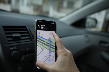 Beyaz bir arabanın arkasında cep telefonu olan bir adam.