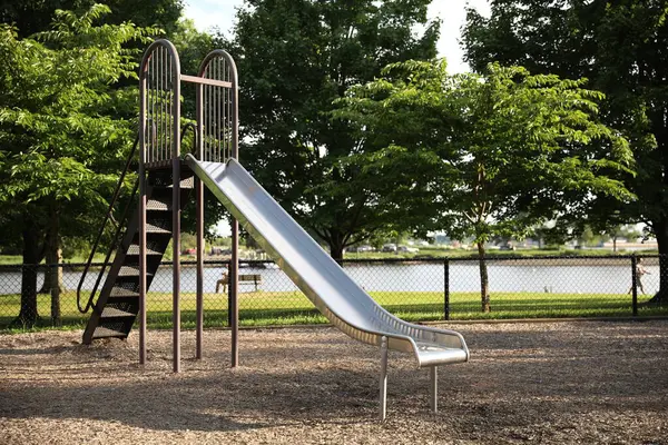 Arka planda tahta merdiven olan metal bir oyun parkının dikey görüntüsü.