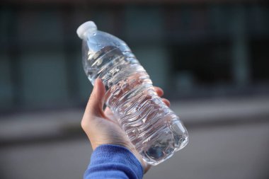 Geçmişi bulanık plastik bir şişe tutan bir kadın.