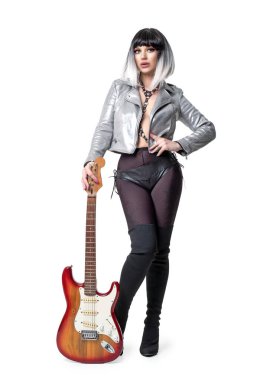 Güzel bir kadın seksi bir elbise ve beyaz arka planda elektro gitar tutan çizmeler giyiyor.