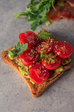 Lezzetli bir tost, taze bir ısırık için kremalı guacamole ve canlı dilimlenmiş vişneli domatesle..