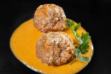 Lezzetli soslu köfteler, sade siyah tabakta servis edilir.