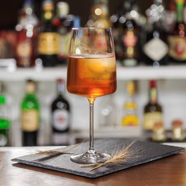 Likörlü Spritz Aperol kokteyli ve barda bir tutam gevrek ile bardaki şişelerin arka planında