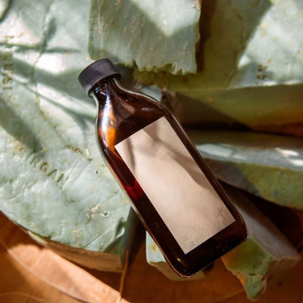 Kozmetik ürünleri için bej etiketli büyük kahverengi şişe ya da güneş ışınlarında yeşil bir sabun çubuğunda şampuan.