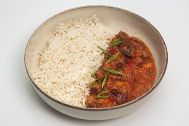 Geleneksel sığır eti veya domuz kebabı güveç, dolmalık biber, soğan ve zengin paprika sosu, buğulanmış beyaz pirinç yanında servis edilir ve seramik tabakta dilimlenmiş yeşil soğanla süslenir. Rahatlatıcı yemekler, yemek blogları ve yemek fotoğrafçılığı için mükemmel..