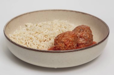 Zengin domates sosuna buharda pişirilmiş beyaz pirinçle seramik kasede servis edilen yumuşak köftelerin üst görüntüsü. Yemek fotoğrafçılığı, tarif blogları ve konforlu gıda projeleri için ideal.