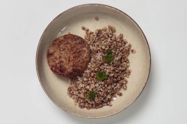 Seramik kasede taze maydanozla süslenmiş pişmiş karabuğday Groats 'un yanında servis edilen ızgara sığır pirzolasının üst görüntüsü. Rahatlatıcı yemek, ev yemeği ve yemek fotoğrafçılığı için ideal.. 