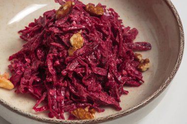 Kremalı sosa batırılmış ve seramik tabakta kavrulmuş cevizle süslenmiş doğranmış pancar salatası manzarası. Sağlıklı beslenme, tarif blogları ve yemek fotoğrafçılığı için ideal..