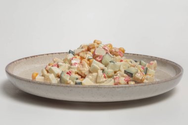 Yengeç çubuğu salatasının en üst görüntüsünde doğranmış taklit yengeç çubukları, salatalık, tatlı mısır ve seramik tabakta kaynamış mayonez sosu karıştırılmış haşlanmış yumurta var. Sağlıklı beslenme, tarif blogları ve yemek fotoğrafçılığı için ideal..