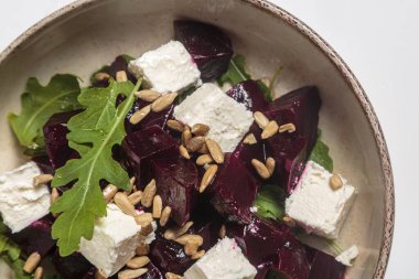 Kavrulmuş pancar kökü küpleri, kremalı feta peyniri, taze roka yaprakları, ayçiçeği çekirdekleri ve seramik kasede mikro yeşillikler içeren canlı pancar salatası. Sağlıklı beslenme, yemek blogları ve yemek fotoğrafçılığı için mükemmel.. 