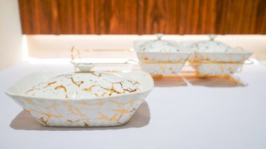 Bu beyaz seramik sebze kasesi masanızın düzenine zarafet katan göz kamaştırıcı altın rengi bir askıyla birlikte geliyor..