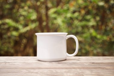 Doğanın bulanık arka planında beyaz seramik bardak