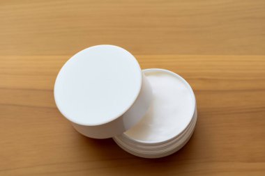 Tahta masadaki beyaz krema kabını kapatın.