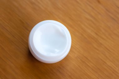 Tahta bir yüzeyde yüz ve vücut bakımı için beyaz yuvarlak krem.