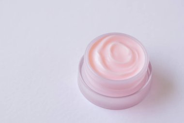 Beyaz arka planda cam kavanozda pembe krem.