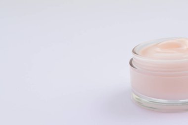 Pembe arka planda yüz kremi olan kavanoz, üst görünüm