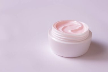 Pembe arka planda krema kavanozu, üst görünüm