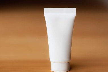 Kahverengi arkaplanda boş beyaz plastik tüp, boşluğu kopyala