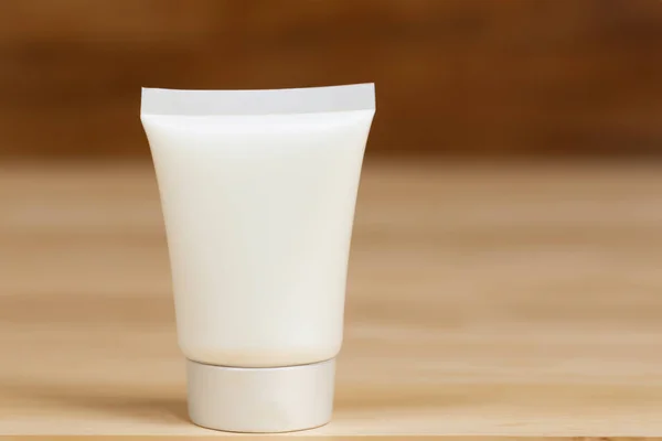 blank tube of cosmetic cream on wooden table, closeup