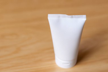 Bej bir arka planda elinde cilt kremi için plastik tüp
