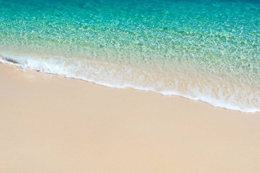 Mavi suyu ve beyaz kumsalı olan plaj ve deniz manzarası..