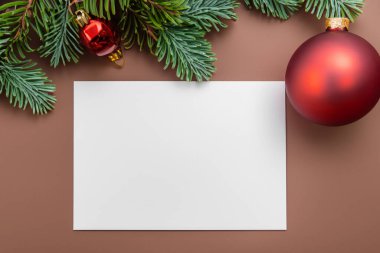 Noel kartı maketi. Noel ağacı ve boş bir kart. Yılbaşı süslemeleri, köknar dalı ve metin için boş kağıt. Arka planda noel kartı modeli