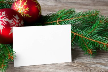 Noel tebrik kartı ve boş beyaz kağıt. Ahşap bir arka planda Noel ağacı dalları. Mesajlaşmak için bir yer..