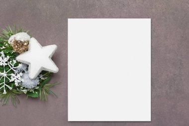 Yılbaşı geçmişi. Boş tebrik kartı, köknar dalları, çam kozalakları ve beyaz süslemeler beyaz bir masanın üstünde düz yatıyordu.