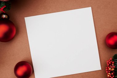 Kırmızı arka planda beyaz kağıt ve boş kağıtlarla noel kartı.