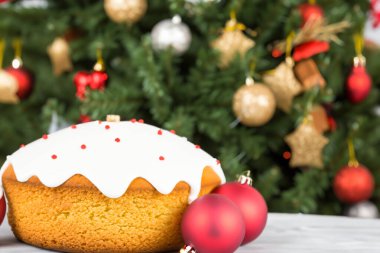 Geleneksel Noel pastası, üzerinde kırmızı krema ve ahşap masa üzerinde Noel ağacı var..