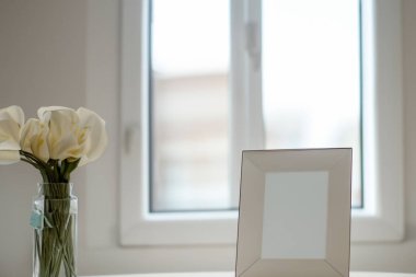 Bir buket gül, çiçekler, mumlar ve camda beyaz bir vazo..