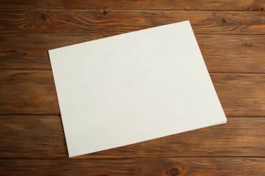 Kahverengi ahşap arkaplan üzerine beyaz kare boş kağıt, kopya alanı ile üst görünüm